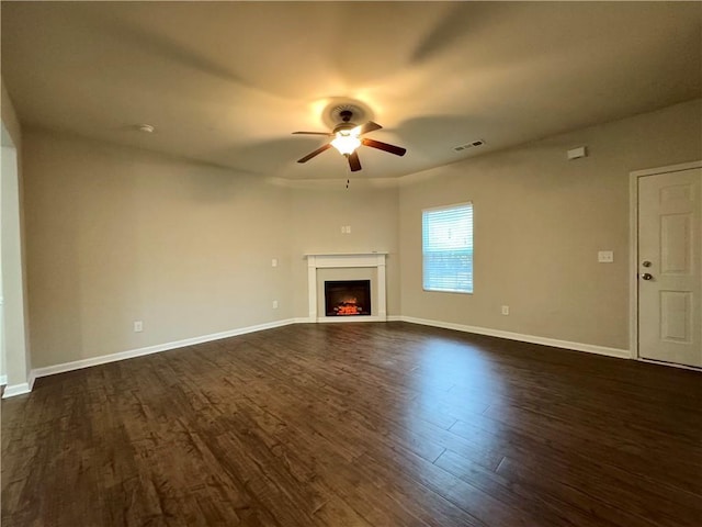 241 Coral Cir, Mcdonough, GA 30253 - unfurnished living room featuring a ceiling fan, dark wood-style flooring, a lit fireplace, and baseboards