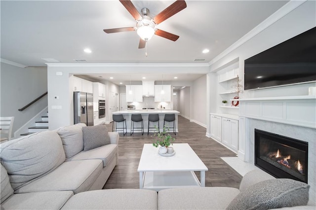 living room featuring ceiling fan, dark hardwood / wood-style floors, a fireplace, ornamental molding, and sink