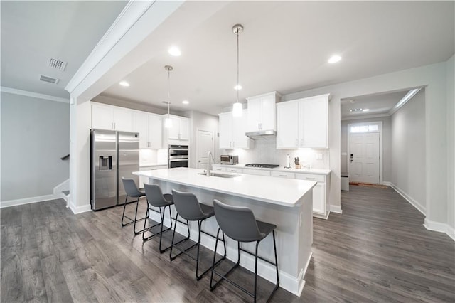 kitchen featuring sink, hanging light fixtures, a kitchen island with sink, appliances with stainless steel finishes, and white cabinets