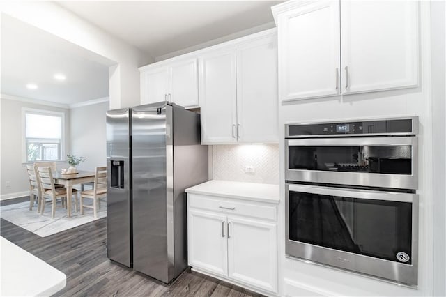 kitchen featuring tasteful backsplash, crown molding, appliances with stainless steel finishes, dark wood-type flooring, and white cabinets