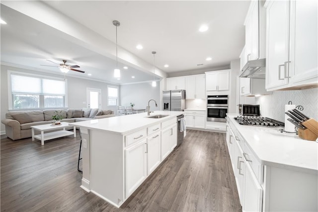 kitchen with decorative light fixtures, white cabinets, a center island with sink, and sink