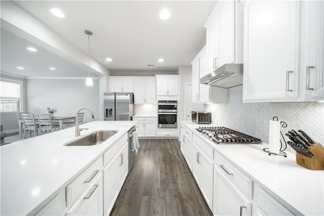 kitchen featuring pendant lighting, white cabinetry, stainless steel appliances, decorative backsplash, and sink