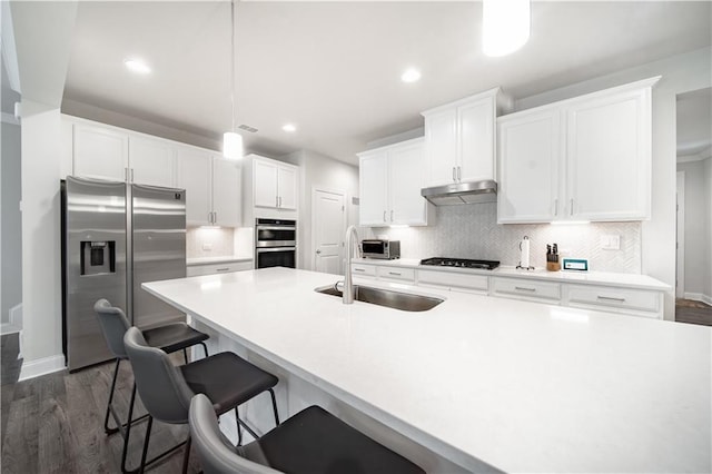 kitchen featuring white cabinetry, stainless steel appliances, dark hardwood / wood-style floors, decorative light fixtures, and sink