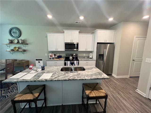 kitchen with a kitchen breakfast bar, dark wood-type flooring, stainless steel appliances, and white cabinets