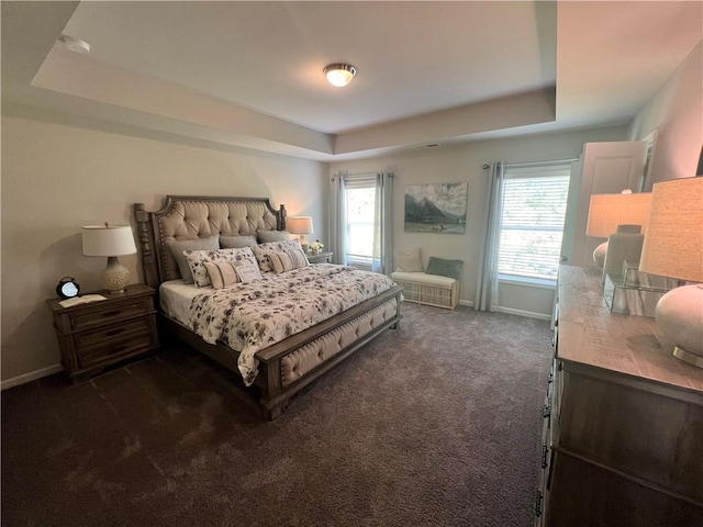 bedroom featuring dark carpet and a tray ceiling