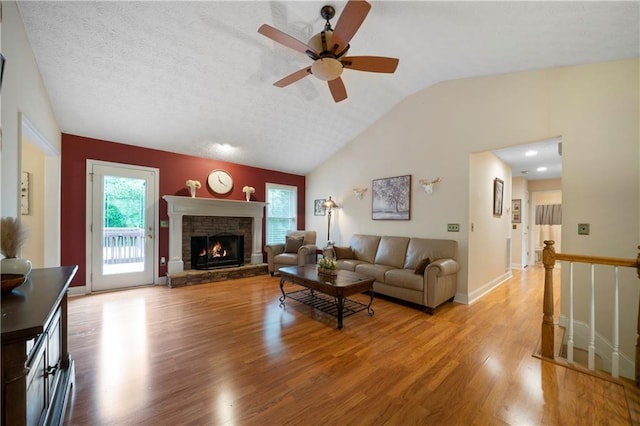 2281 Carlan Rd, Jasper, GA 30139 - living area featuring vaulted ceiling, light wood-type flooring, a ceiling fan, a stone fireplace, and baseboards