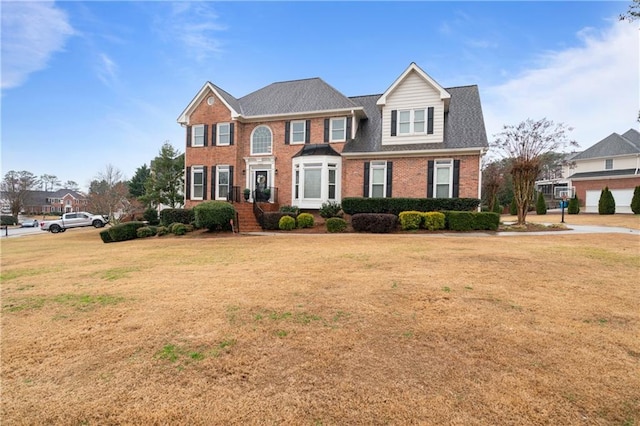 view of front facade featuring brick siding, a shingled roof, and a front yard