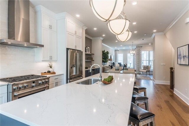 kitchen with crown molding, hardwood / wood-style floors, wall chimney exhaust hood, pendant lighting, and high end appliances