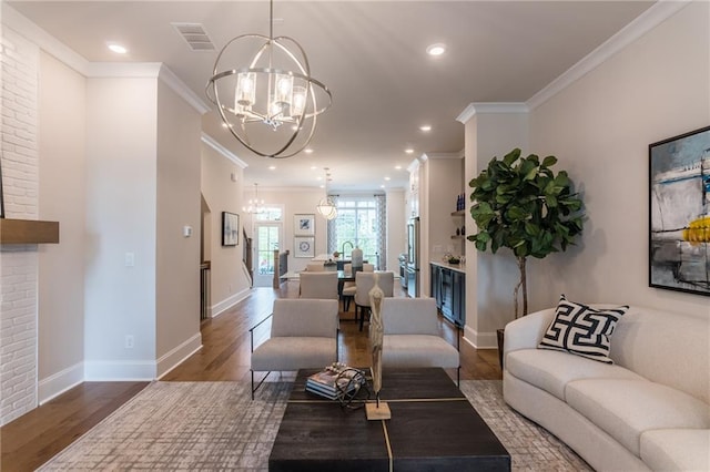 living room with brick wall, an inviting chandelier, hardwood / wood-style floors, and ornamental molding