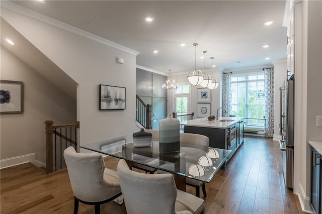 dining area featuring an inviting chandelier, sink, ornamental molding, and dark hardwood / wood-style floors