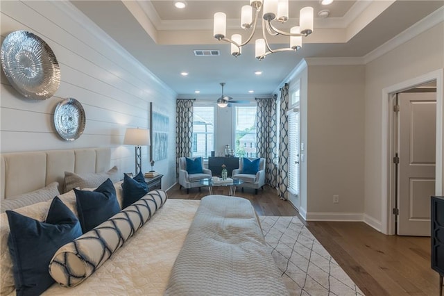 bedroom featuring wood-type flooring, a raised ceiling, crown molding, and a chandelier