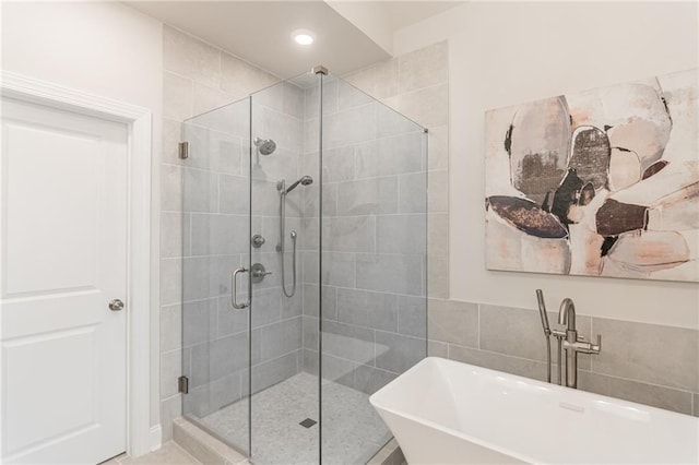 bathroom featuring sink, separate shower and tub, and tile walls