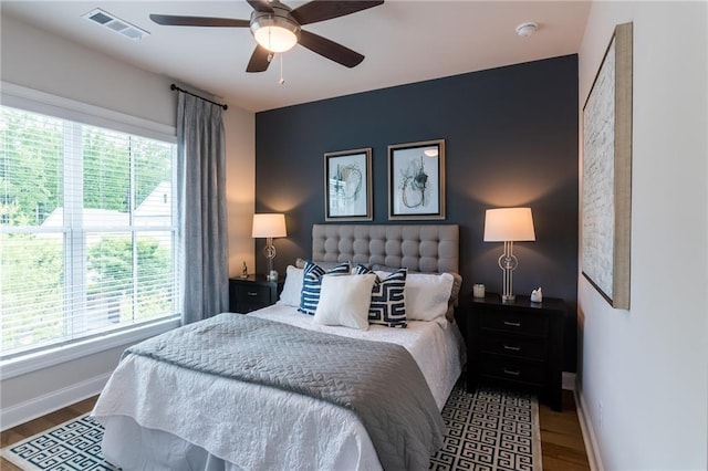 bedroom with multiple windows, hardwood / wood-style flooring, and ceiling fan