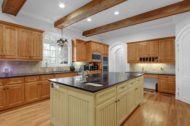 kitchen with light wood-type flooring, beamed ceiling, hanging light fixtures, decorative backsplash, and a center island with sink