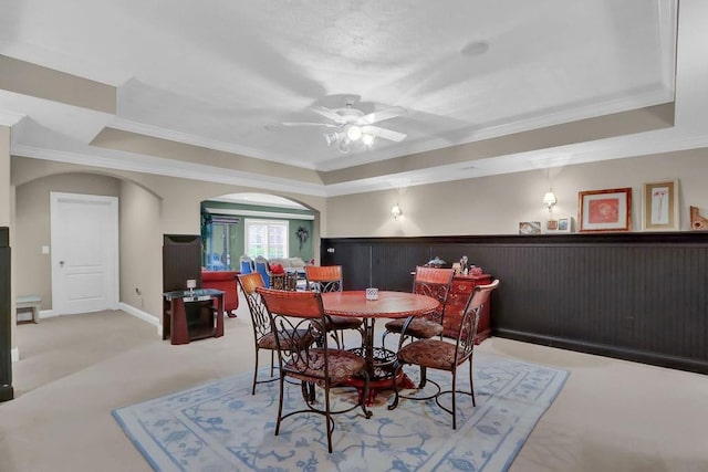 carpeted dining area featuring crown molding, a raised ceiling, and ceiling fan