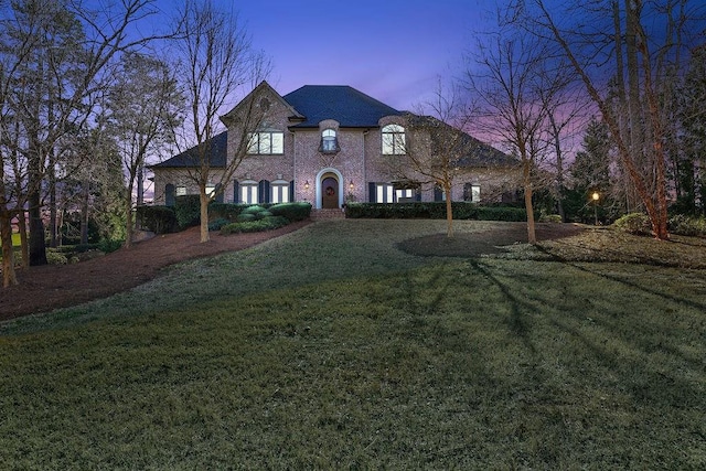 back house at dusk with a lawn