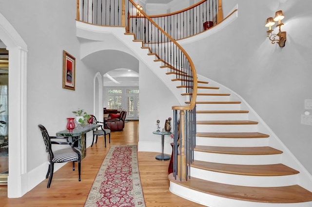 staircase with wood-type flooring and a towering ceiling