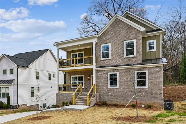 view of front of house with brick siding, board and batten siding, metal roof, a balcony, and a standing seam roof