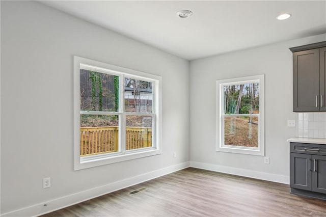 unfurnished dining area with visible vents, recessed lighting, wood finished floors, and baseboards