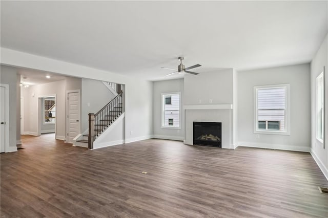 unfurnished living room featuring dark wood finished floors, stairway, a fireplace, and baseboards