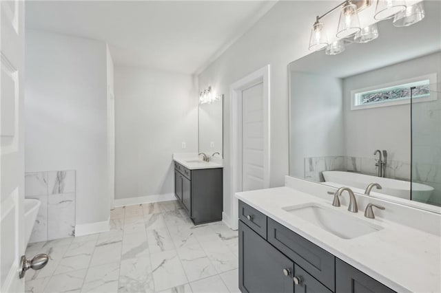 full bathroom featuring a sink, a freestanding tub, baseboards, and marble finish floor