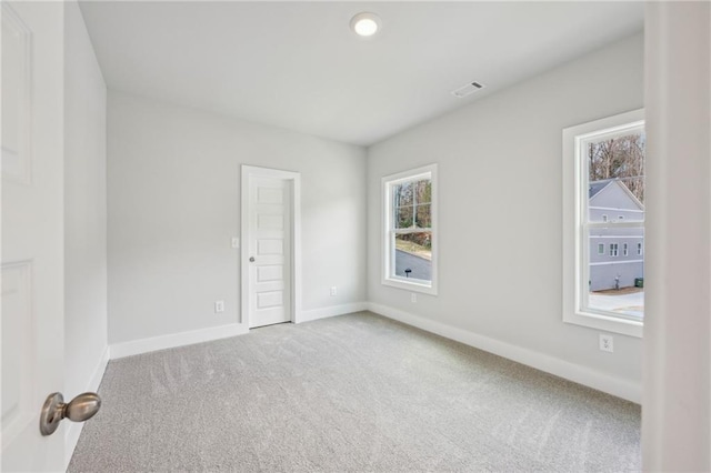 spare room featuring baseboards, carpet floors, and visible vents