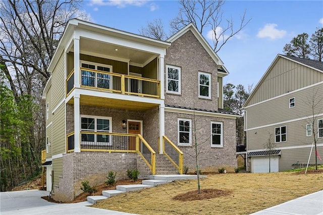 view of front of home featuring a standing seam roof, a porch, a balcony, and brick siding