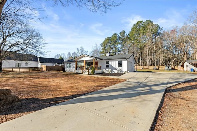 view of front of house with covered porch, concrete driveway, and fence