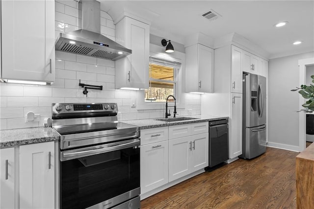 kitchen featuring visible vents, a sink, white cabinetry, appliances with stainless steel finishes, and wall chimney range hood