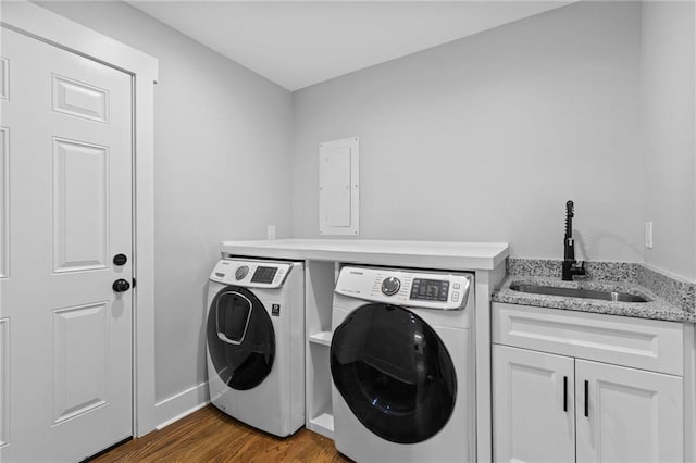 washroom with wood finished floors, baseboards, cabinet space, separate washer and dryer, and a sink