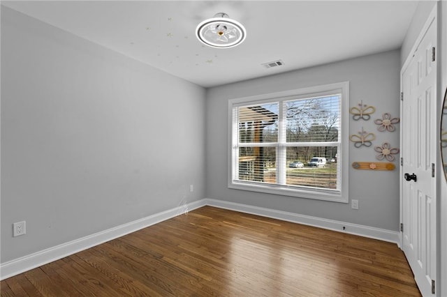 unfurnished room with visible vents, baseboards, and wood finished floors