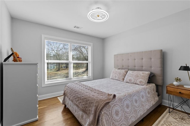 bedroom with visible vents, baseboards, and wood finished floors