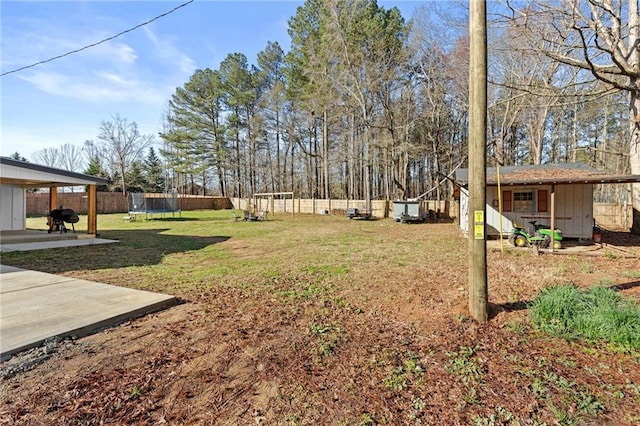 view of yard featuring an outbuilding, a trampoline, a fenced backyard, and a patio area