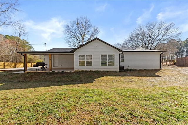 rear view of house featuring a carport, a lawn, a patio, and fence