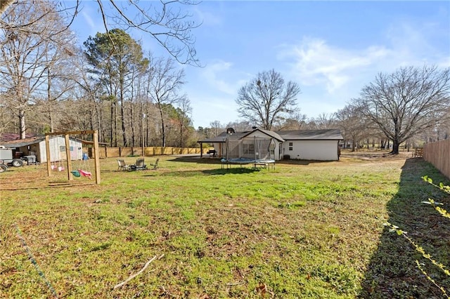 view of yard featuring an outdoor structure, a trampoline, and fence