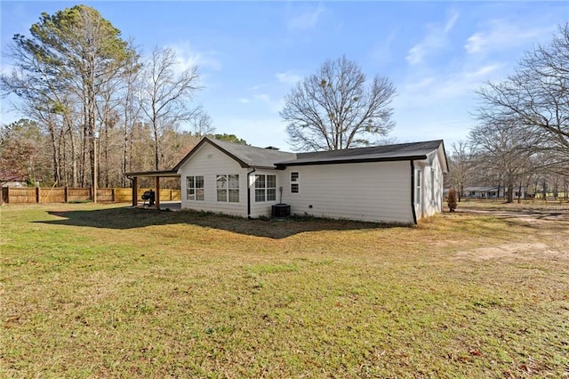 rear view of house featuring fence and a lawn