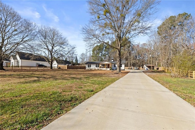 view of yard with concrete driveway and fence