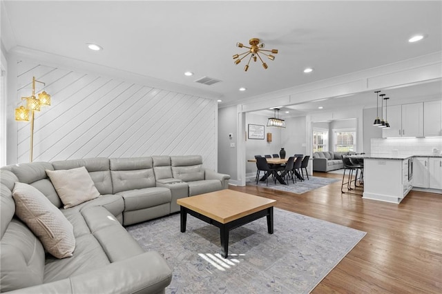 living room with recessed lighting, visible vents, crown molding, and light wood finished floors