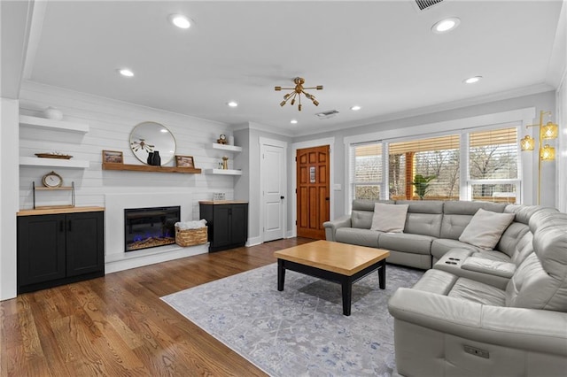 living area featuring dark wood finished floors, crown molding, recessed lighting, and a glass covered fireplace