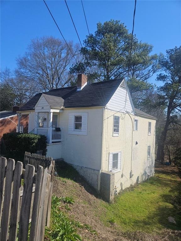 view of side of property with a chimney and fence