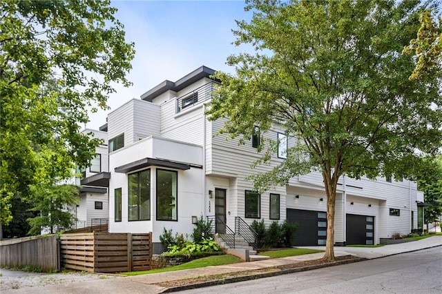 multi unit property featuring a garage, fence, and driveway