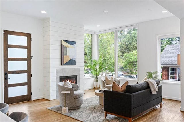 living room with a glass covered fireplace, plenty of natural light, recessed lighting, and wood finished floors