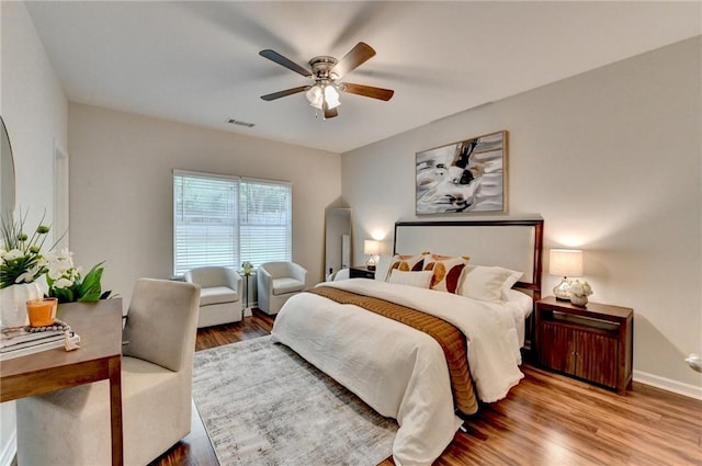bedroom featuring a ceiling fan, baseboards, visible vents, and wood finished floors