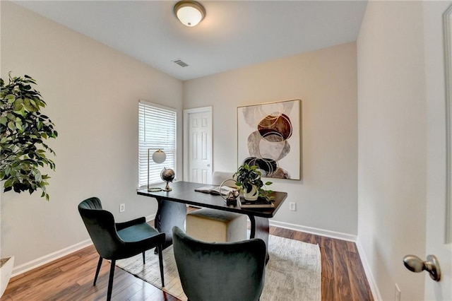office area with baseboards, visible vents, and wood finished floors