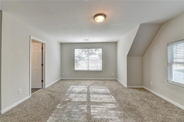 additional living space with baseboards, plenty of natural light, and carpet