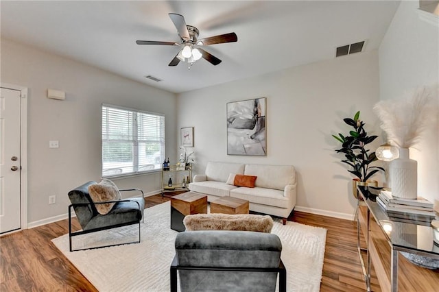 living area featuring a ceiling fan, baseboards, visible vents, and wood finished floors