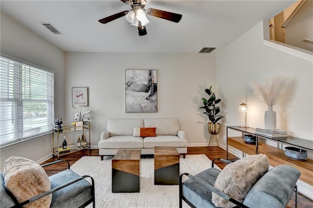 living area featuring baseboards, a ceiling fan, wood finished floors, and visible vents