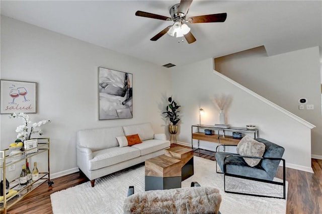 living room featuring a ceiling fan, baseboards, wood finished floors, and stairway
