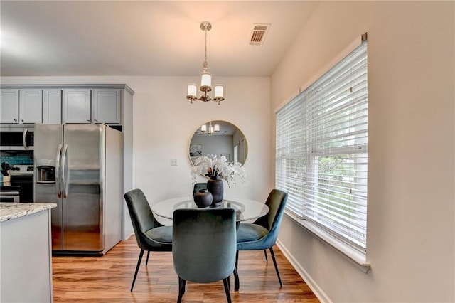 dining area featuring an inviting chandelier, visible vents, and light wood-type flooring