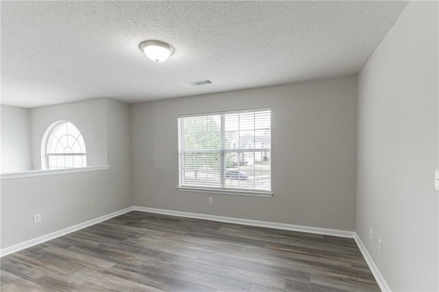 empty room with a wealth of natural light, hardwood / wood-style flooring, and a textured ceiling